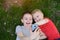 Two boys make selfie on a smartphone while lying on the grass. Top view