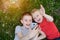 Two boys make selfie on a smartphone while lying on the grass. Top view