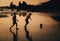 Two boys play soccer on beach in dusk, Goa, India