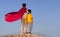 Two boys playing superheroes on the sky background, Superhero protects younger friend