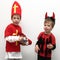 Two boys presenting Saint Nicholas with gift stocking and little devil