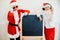 Two boys pretending he is a Bad Santa near black board