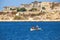 Two boys rowing in the boat on the water of Grand Harbour with t