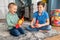 Two boys with rubber animal figures sitting on the floor