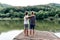 Two boys stand on the pier by the lake.