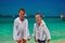 Two boys on sunny tropical beach look at camera. Children are dressed in shirts to protect themselves from ultraviolet exposure.