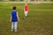 Two boys in uniform playing football on the green grass