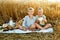 Two boys and a white pigeon in a wheat field. Children and a picnic on a rye bread field in summer at sunset