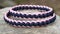 two bracelets sitting on top of a rock next to each other on top of a stone slab with a pink and blue braid on it