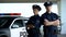 Two brave policemen in uniform and service cap posing near patrol car, order