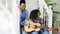 Two brazilian curly girls sistres sitting on stairs and practice to play acoustic guitar. Friends have fun and singing