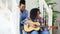 Two brazilian curly girls sistres sitting on stairs and practice to play acoustic guitar. Friends have fun and singing