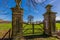 Two brick pillars of a wooden and wrought iron gate in a farm, Dutch countryside