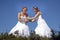 Two brides play rugby in wedding dress against blue sky