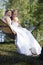 Two brides pose on hammock in forest on sunny summer day