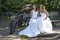 Two brides pose on wooden bench in forest with mountain bikes ne