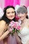 Two brides wearing white dresses hold bouquet