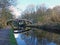 Two bridges crossing the leeds to liverpool canal in armley with trees reflected on the water and footpath