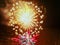 Two bright blurry flashes of fireworks in golden and blue color with crimson sparks against the background of a dark