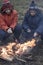 Two brother roasting hotdogs on sticks at bonfire. Children havi