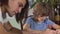 Two brothers drawing intently on paper sitting at the table together. Brothers relationship.