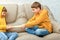 Two brothers fight sitting on the couch and can`t share a baseball bat