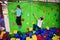 Two brothers kids climbing on a green wall in attraction playground