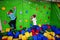 Two brothers kids climbing on a green wall in attraction playground