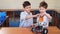 Two brothers kids playing with robot toy at school robotics class, indoor.