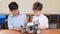 Two brothers kids playing with robot toy at school robotics class, indoor.