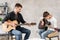 Two brothers learn to play acoustic guitar. The older brother tunes the guitar while the younger one runs his finger