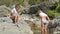 Two brothers, little boys walk barefoot on the mountain stream.