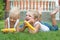 Two brothers lying on the grass and eat corn on the cob in the garden