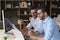 Two brothers partners working together seated at desk with computers