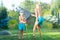 Two brothers play on a summer hot day in the garden. Children are splashing with a garden hose.