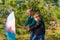 Two brothers are pulling a colored umbrella against the wind in a pine forest