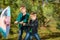 Two brothers are pulling a colored umbrella against the wind in a pine forest