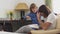 Two brothers sitting on arm chair, older brother read for small brother a book and young boy touching brothers long hair