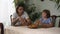 Two brothers sitting on the kitchen table talking and eating croissant and drink cappuccino. Older and younger brothers