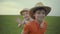 Two brothers are walking in the field in straw hats in the summer.