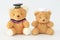Two brown bear dolls wearing a graduation cap and a nurse hat.