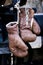 Two brown boxing gloves hanging from a steel handle