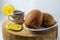 Two brown breads on a plate and one cup of warm lemon tea are placed on a wooden mat with an isolated white background