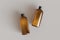 Two brown plastic cosmetic containers, shampoo bottles laying on gray background front view 3D render mockup