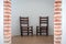 Two brown school chairs with white wall on background in natural daylight