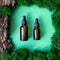 Two brown serum or oil glass mock up bottles with pipette over natural green background of tree bark and moss