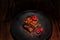 Two Brownies and Raspberries on a black plate on dark wood table