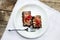 Two brownies with redberries on top, served in a plate on a wooden table