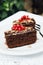 Two brownies with redberries on top, served in a plate on a wooden table