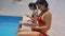 Two brunette girls in bikinis are using their mobile phones while sitting in the pool